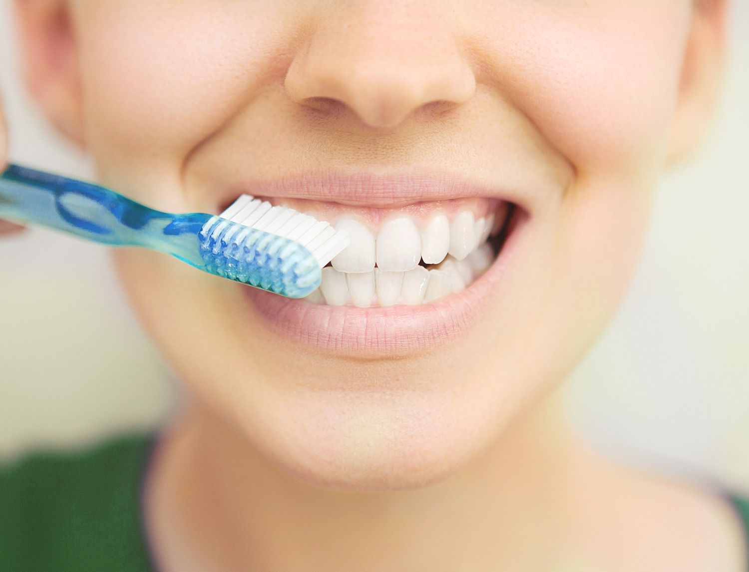 Primo piano di una bocca sorridente mentre viene spazzolata con uno spazzolino blu e bianco