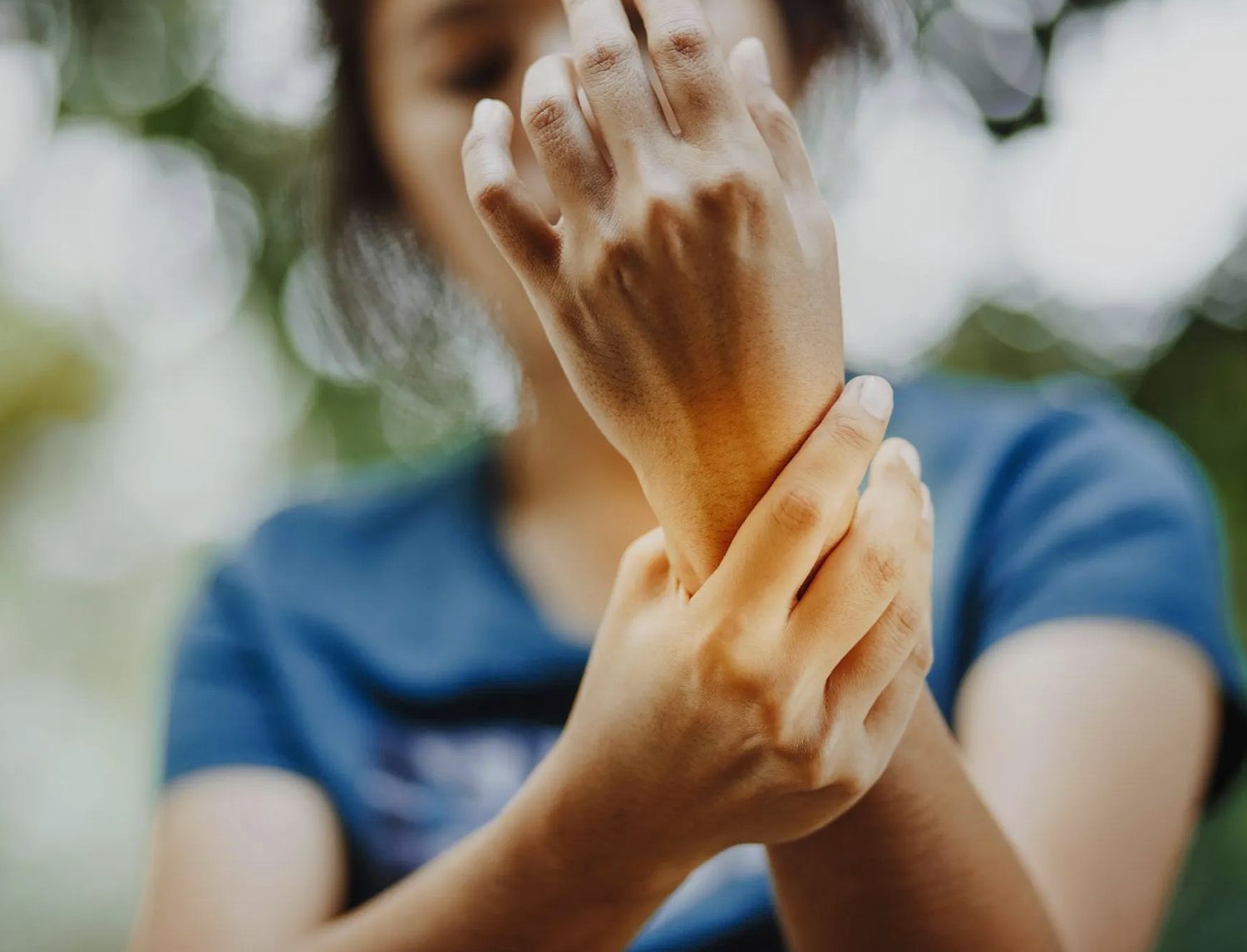 Primo piano di una persona che si tiene il polso con l'altra mano, all'aperto